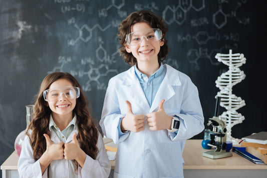 A young boy and girl wearing labcoats and safety goggles have fun with science at home.
